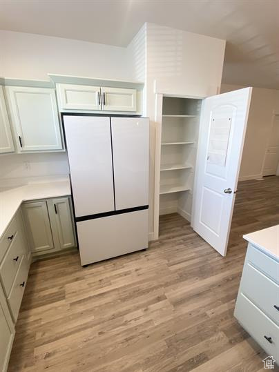 Kitchen with freestanding refrigerator, light wood-type flooring, and light countertops
