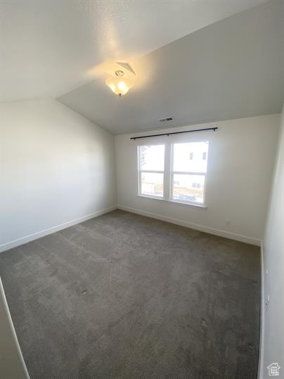 Carpeted empty room with lofted ceiling and baseboards