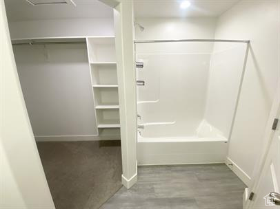 Full bathroom with tub / shower combination, a spacious closet, and wood finished floors
