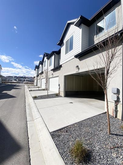 View of property exterior with an attached garage, driveway, stucco siding, and a residential view