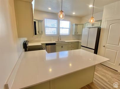 Kitchen with freestanding refrigerator, range, a peninsula, dishwasher, and light countertops