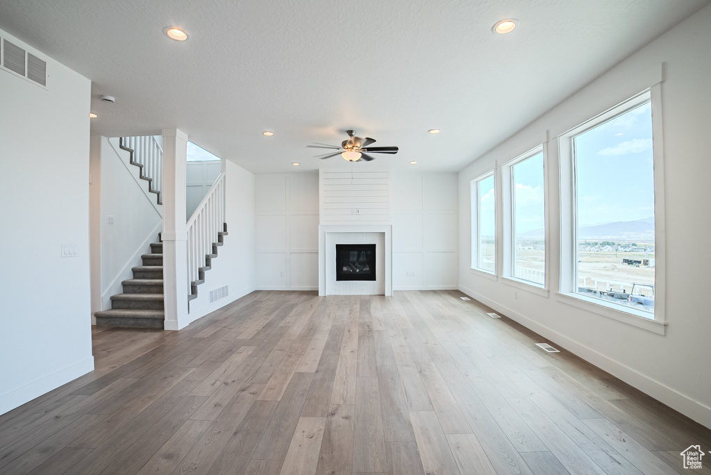 Unfurnished living room with a ceiling fan, stairs, hardwood / wood-style floors, a fireplace, and recessed lighting