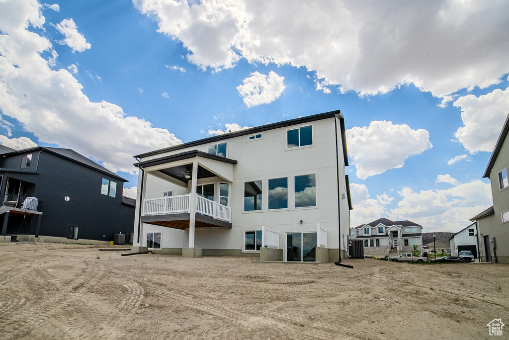 Rear view of property featuring a balcony, stucco siding, and a residential view