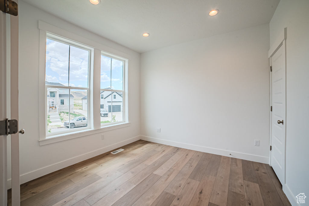 Empty room with healthy amount of natural light, light wood finished floors, and recessed lighting