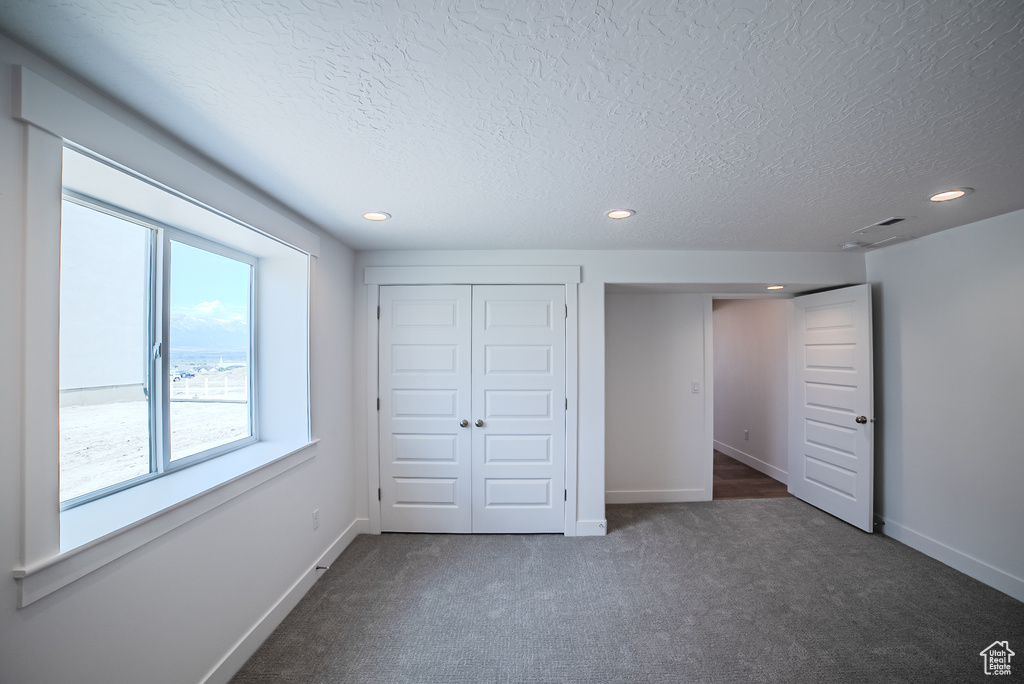 Unfurnished bedroom with carpet flooring, a textured ceiling, recessed lighting, and a closet