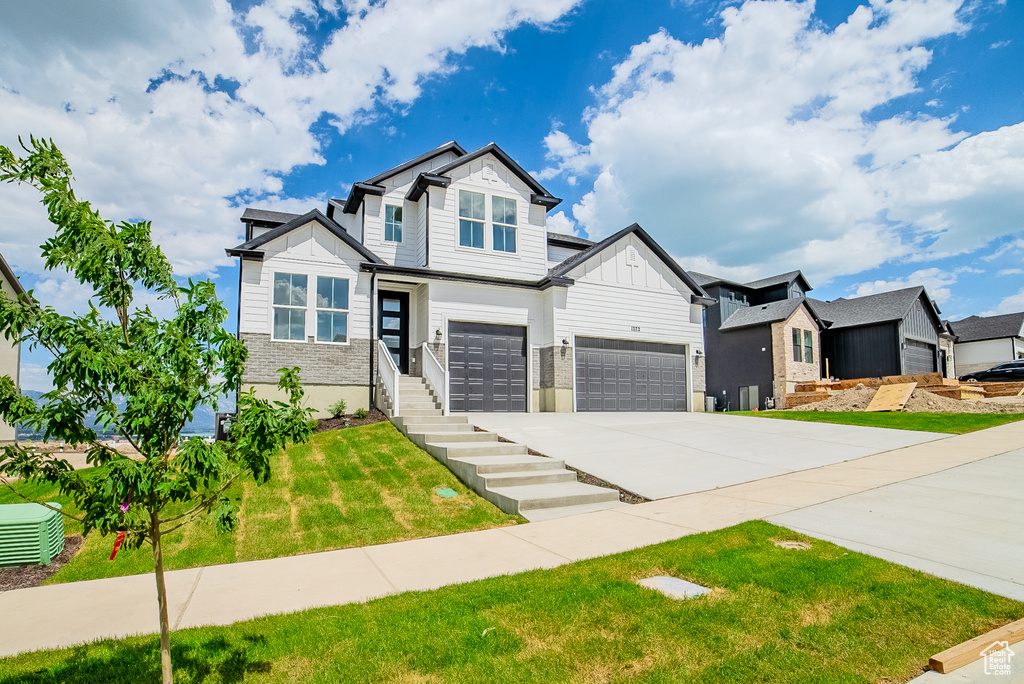 View of front of home with concrete driveway, board and batten siding, a front lawn, a residential view, and a garage