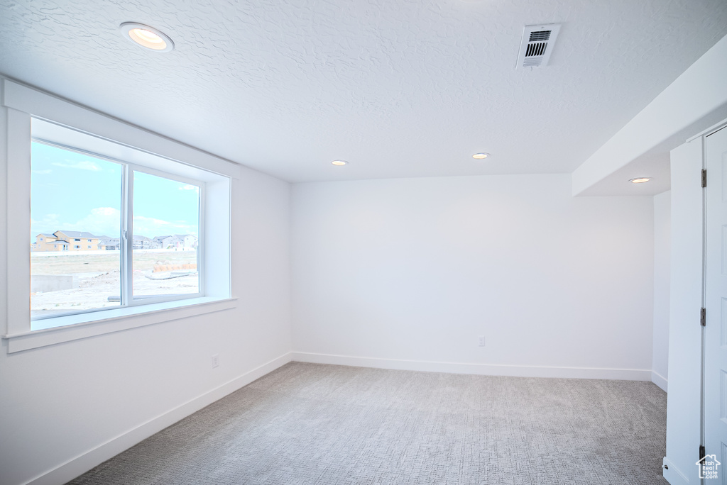 Empty room featuring recessed lighting, light colored carpet, and a textured ceiling