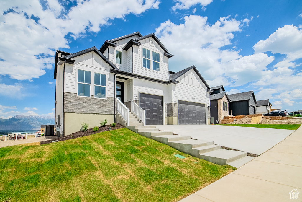 View of front of property with concrete driveway, board and batten siding, a front yard, a mountain view, and an attached garage