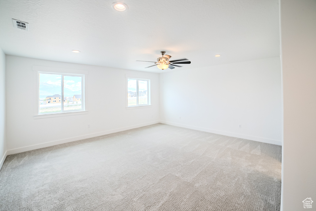 Empty room with light carpet, a ceiling fan, and recessed lighting