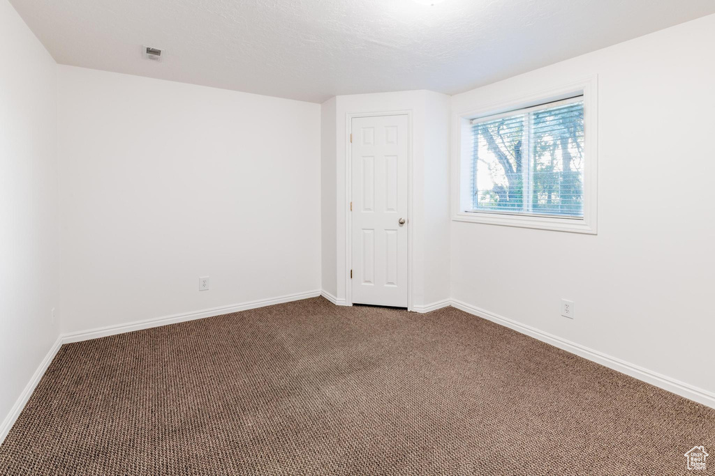 Unfurnished room featuring dark carpet and baseboards
