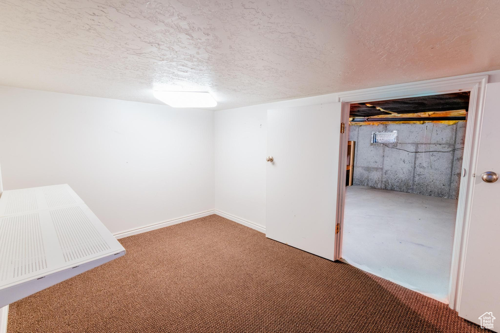 Finished below grade area featuring a textured ceiling and carpet