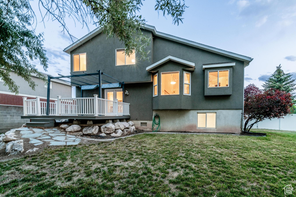 Back of property with a wooden deck and stucco siding