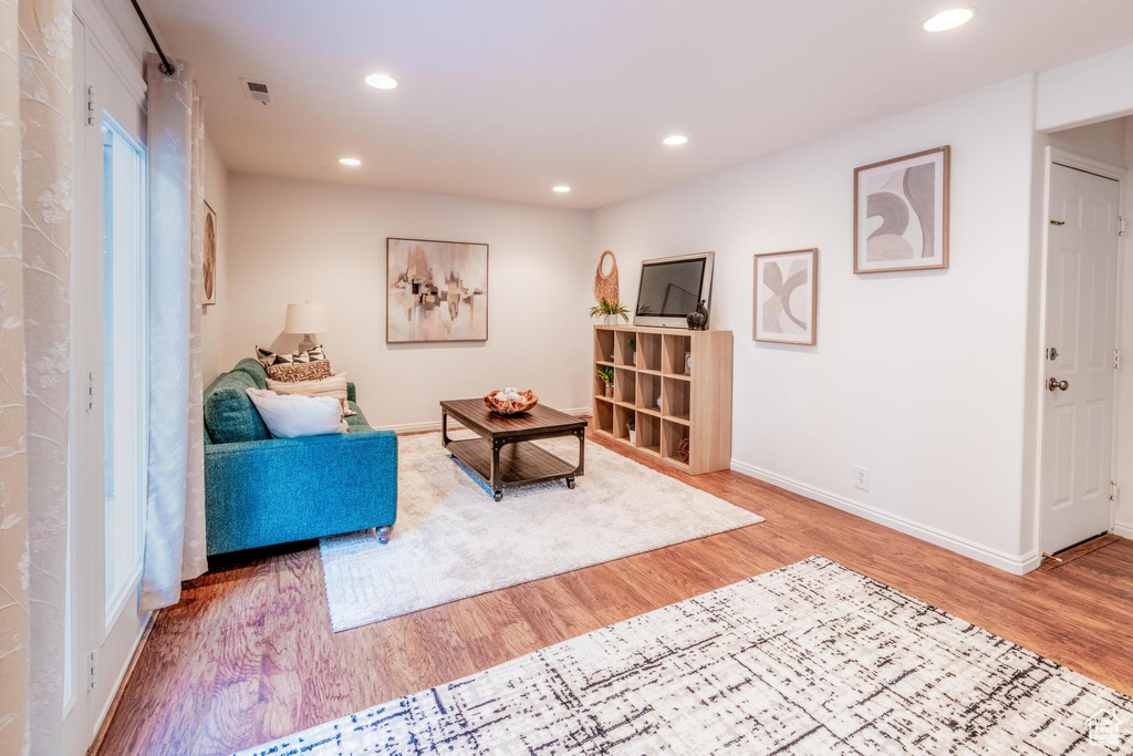 Living area with light wood-type flooring and recessed lighting