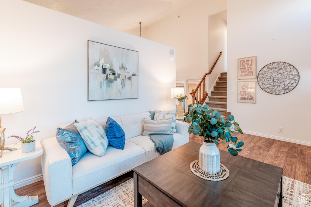 Living area with stairway, wood finished floors, and high vaulted ceiling