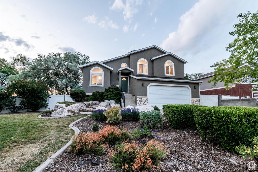Traditional-style home featuring stucco siding, stone siding, and a garage