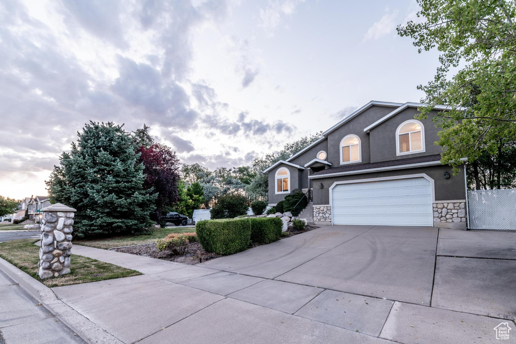 View of front of home featuring concrete driveway, stone siding, stucco siding, and an attached garage