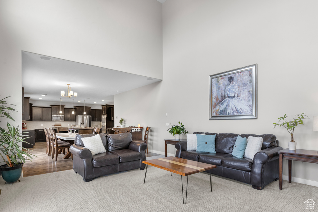 Living area with a chandelier, a towering ceiling, recessed lighting, and light wood-type flooring