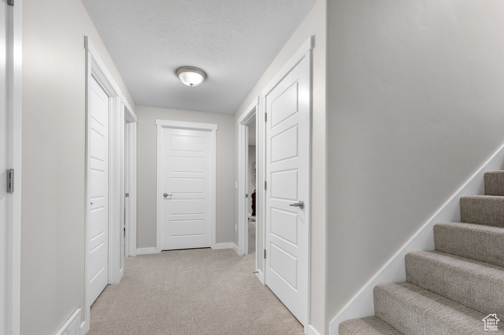 Corridor with light carpet and a textured ceiling