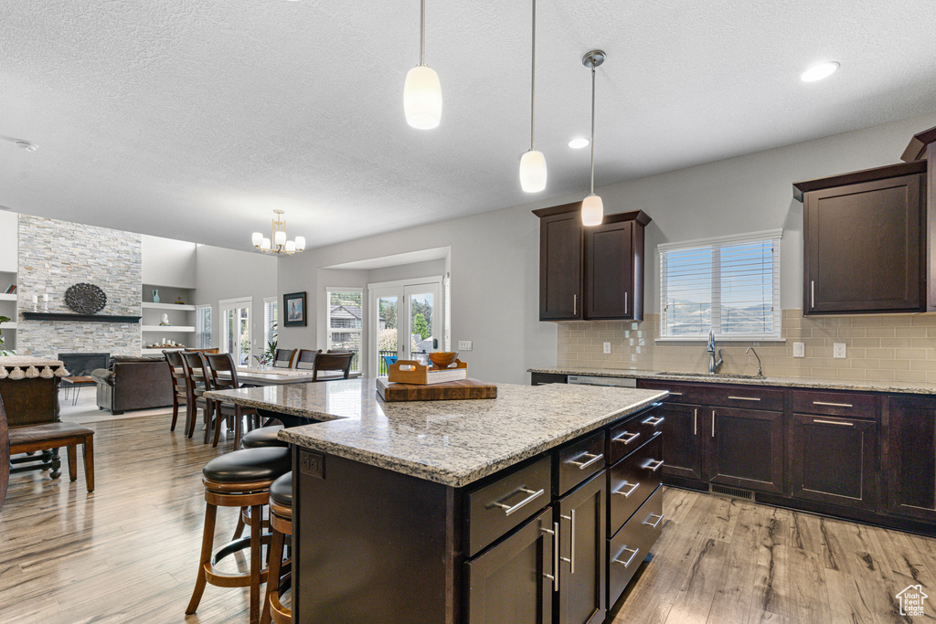 Kitchen with light wood-style floors, a kitchen breakfast bar, backsplash, a textured ceiling, and recessed lighting