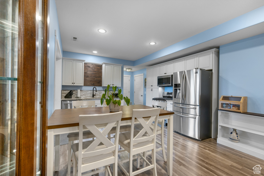 Kitchen with stainless steel appliances, white cabinetry, light wood-style floors, recessed lighting, and light countertops