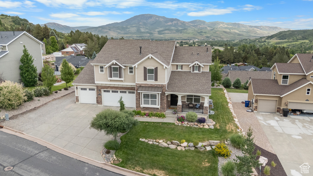 View of front of property with covered porch, concrete driveway, a mountain view, a residential view, and a front lawn