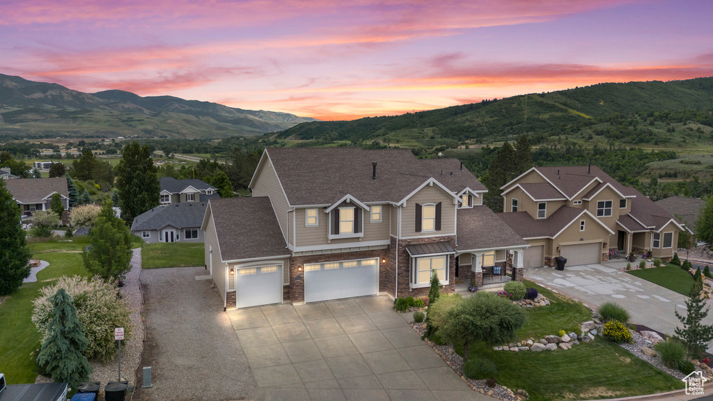 View of front of property featuring driveway, a mountain view, a garage, and covered porch