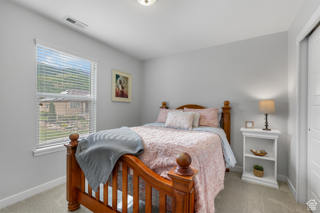 Bedroom with carpet flooring, multiple windows, and a closet