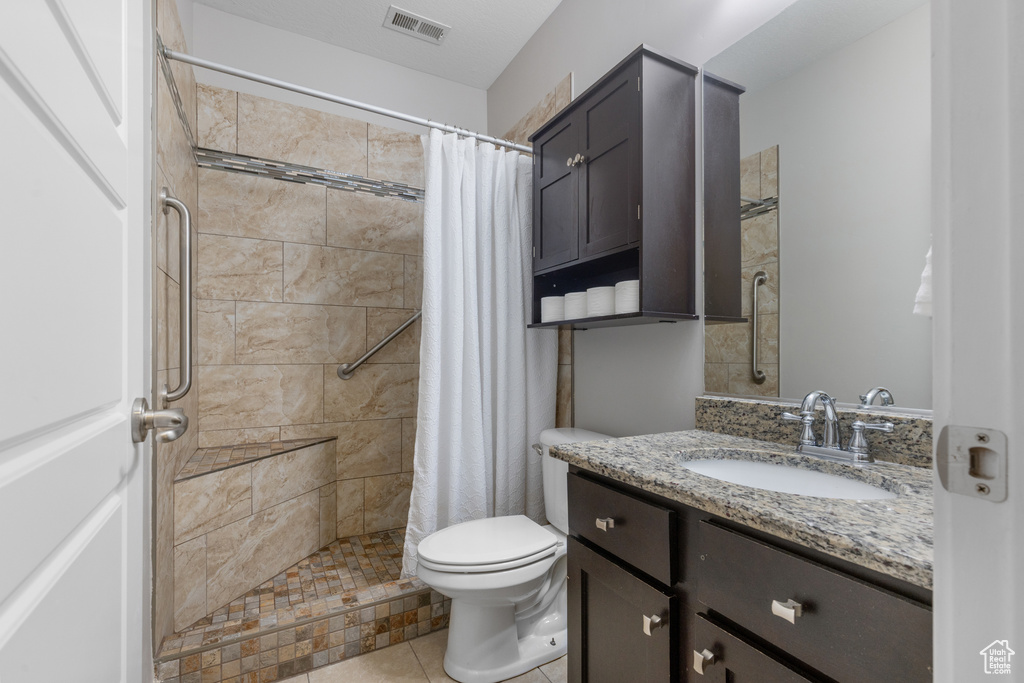 Bathroom with vanity, a tile shower, and tile patterned flooring