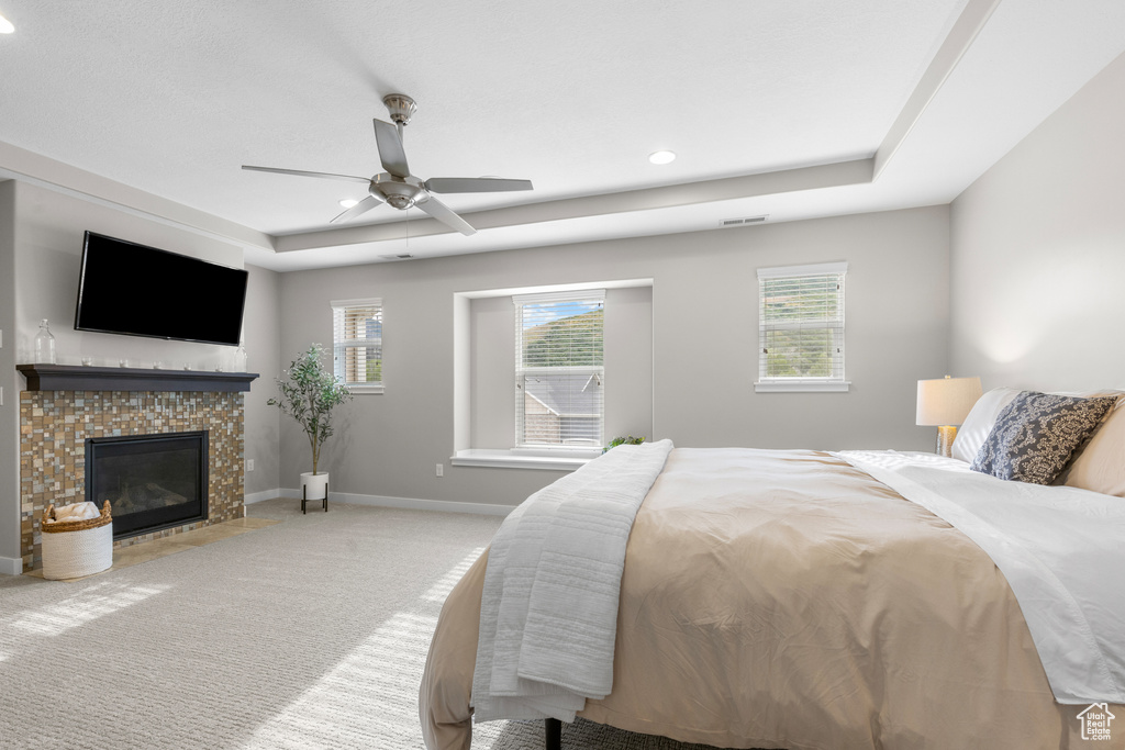 Bedroom featuring a raised ceiling, carpet, a fireplace, ceiling fan, and recessed lighting