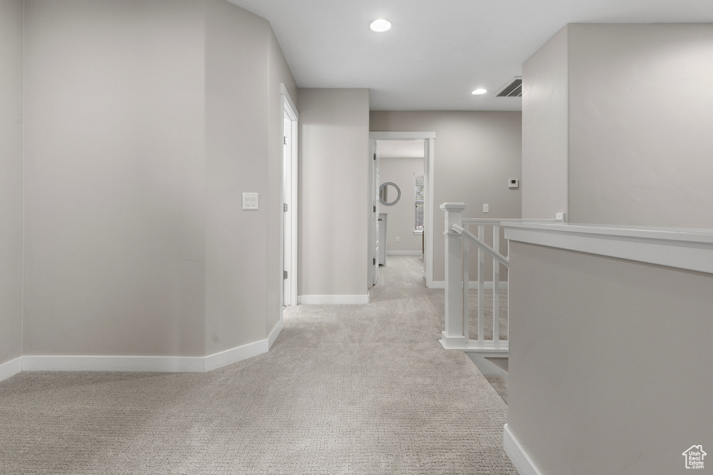 Hallway featuring an upstairs landing, light colored carpet, and recessed lighting
