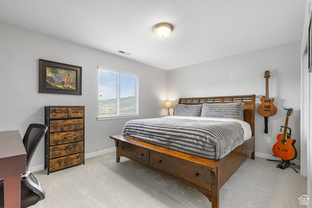 Bedroom featuring light carpet and an office area