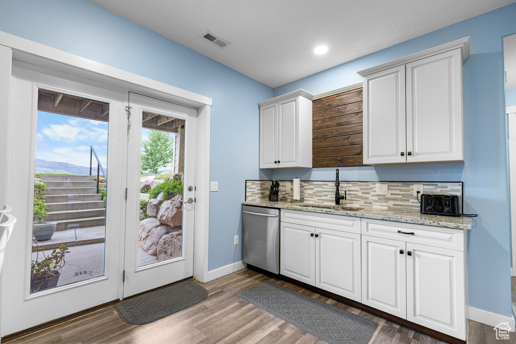 Kitchen featuring stainless steel dishwasher, wood finished floors, decorative backsplash, white cabinets, and recessed lighting