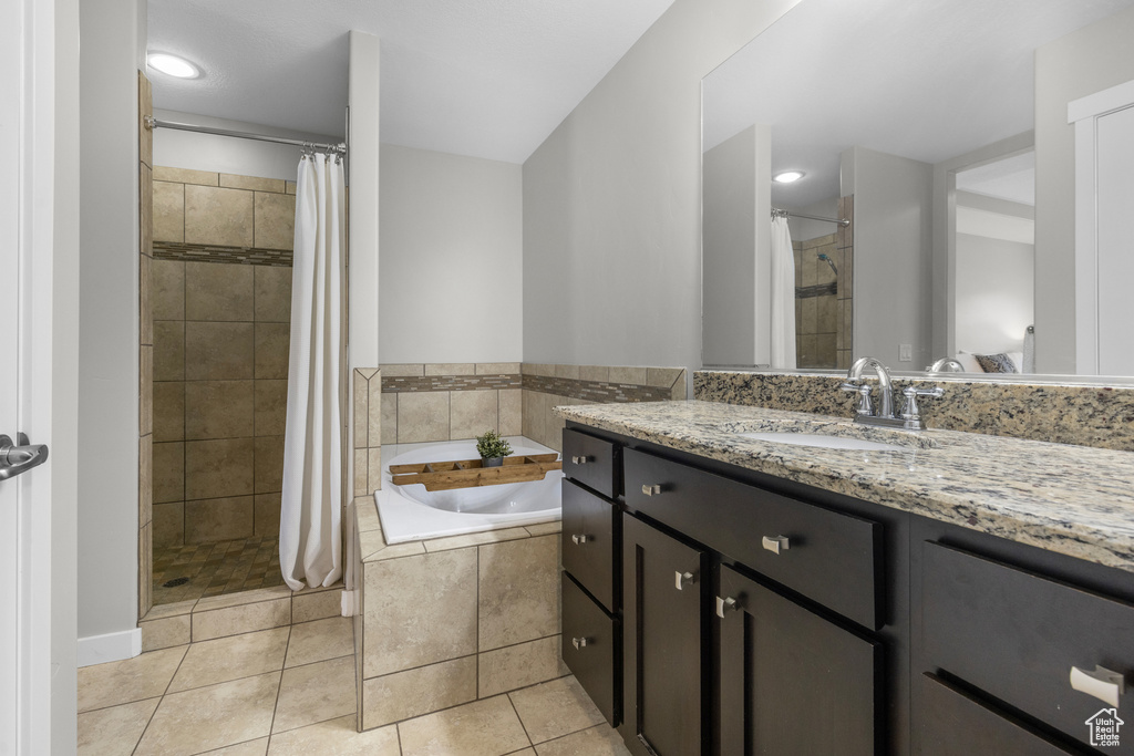 Bathroom featuring a garden tub, a tile shower, vanity, and tile patterned flooring