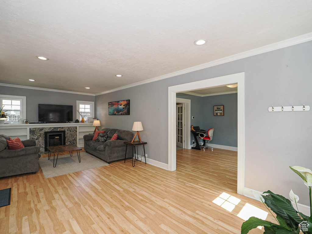 Living area featuring light wood finished floors, recessed lighting, crown molding, and a fireplace