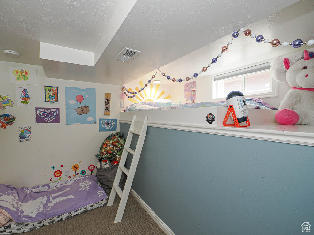 Carpeted bedroom featuring a textured ceiling and baseboards