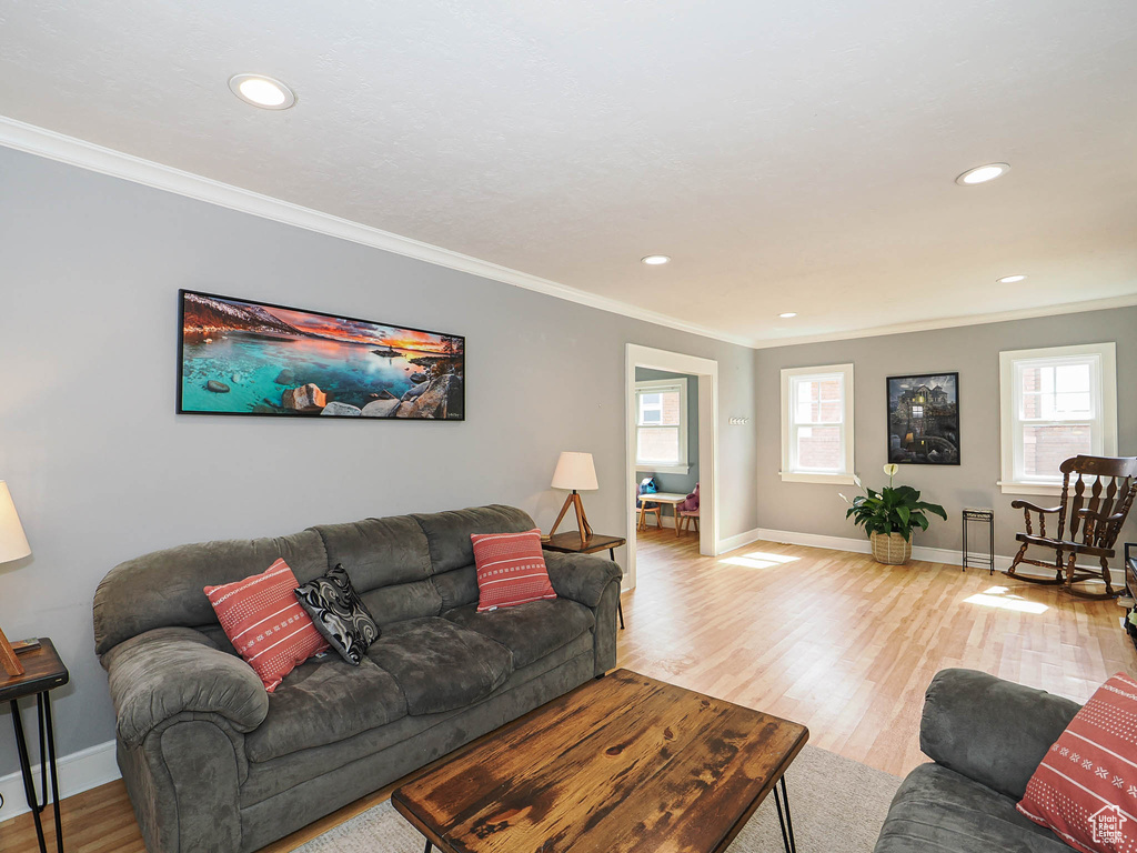 Living area featuring crown molding, healthy amount of natural light, wood finished floors, and recessed lighting