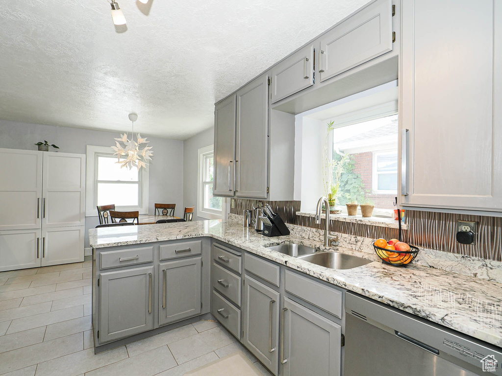 Kitchen with stainless steel dishwasher, gray cabinetry, a peninsula, light tile patterned flooring, and a textured ceiling