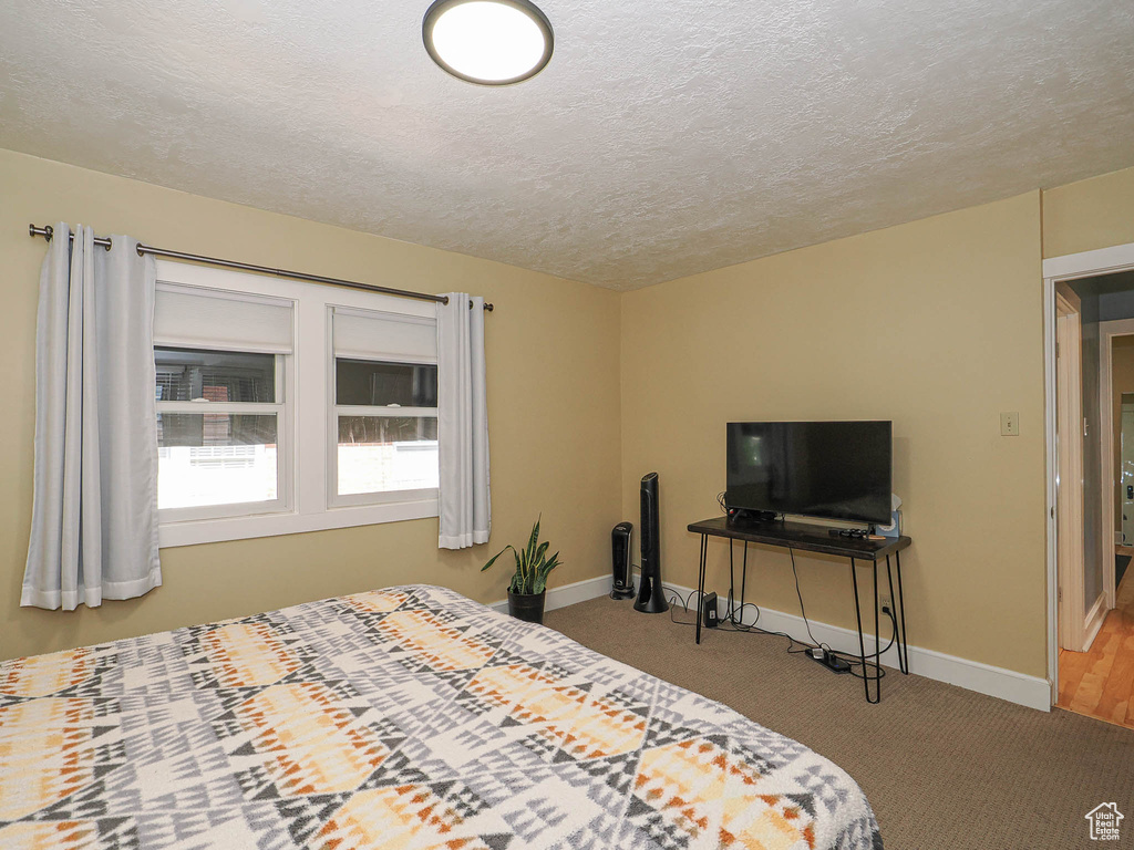 Carpeted bedroom featuring baseboards and a textured ceiling