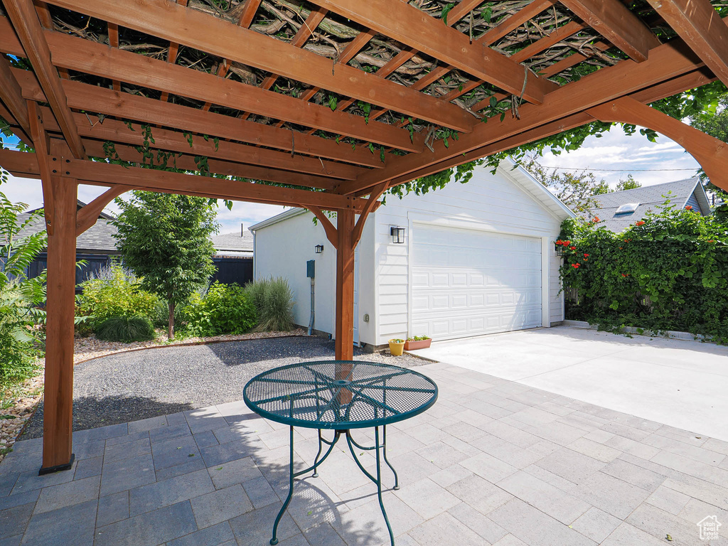 View of patio / terrace featuring a pergola, an outbuilding, a garage, and driveway