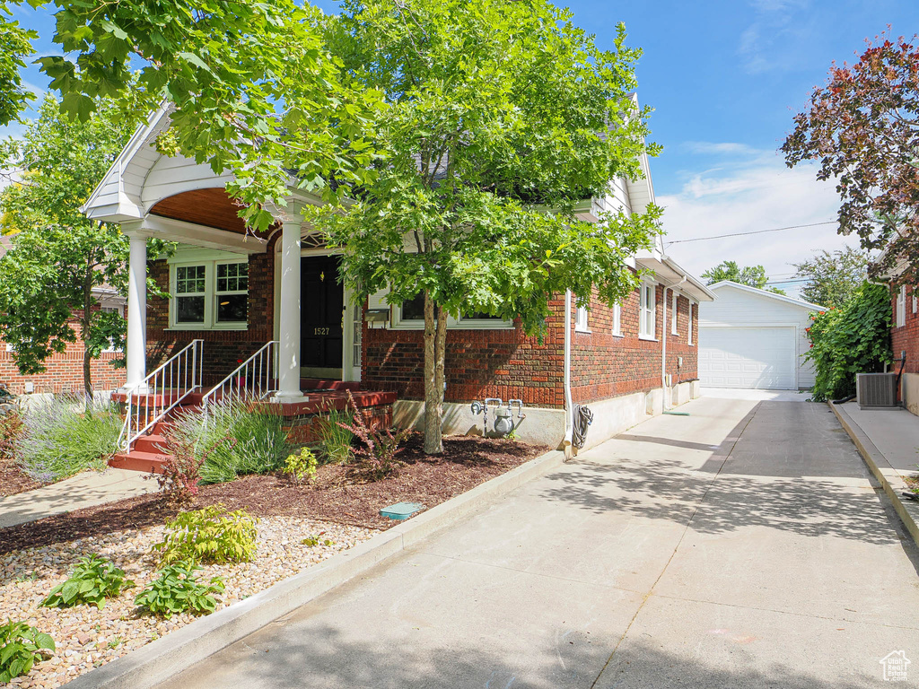 View of front of home featuring brick siding, an outdoor structure, and a garage