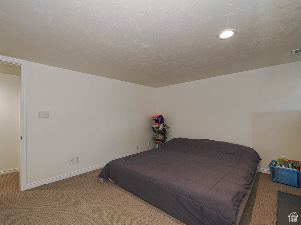 Bedroom with carpet, a textured ceiling, and recessed lighting