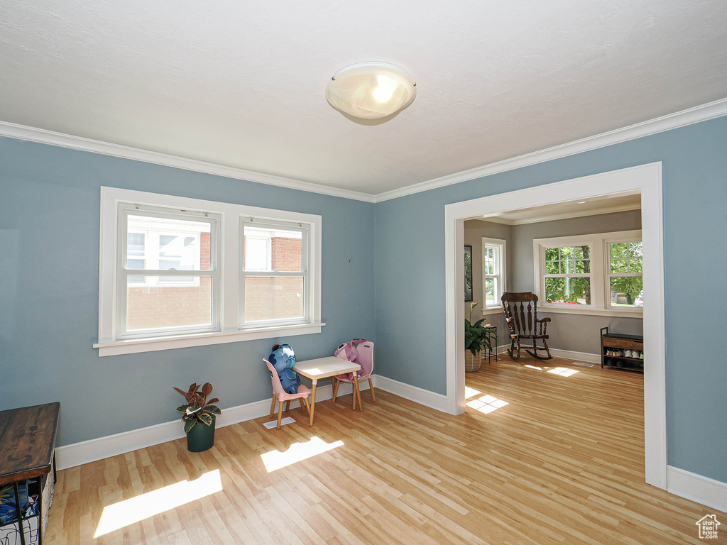 Living area with crown molding and light wood-type flooring