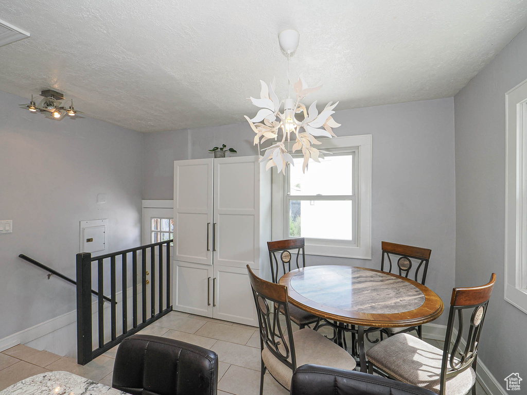 Dining room featuring a chandelier, light tile patterned floors, and a textured ceiling