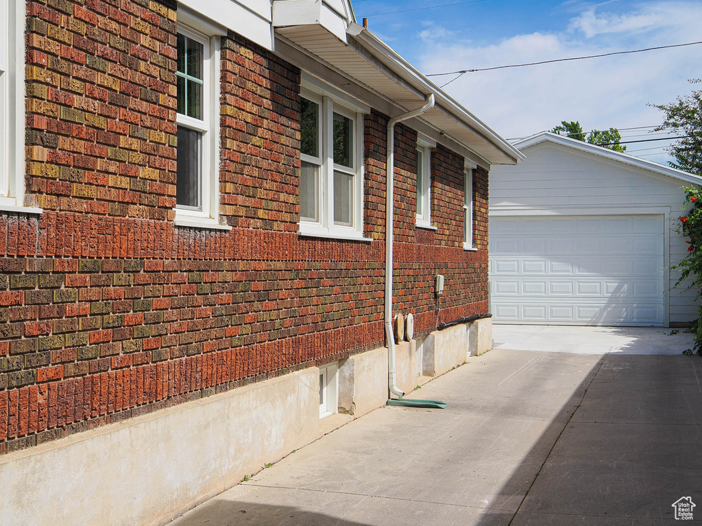 View of side of home with brick siding, an outbuilding, and driveway