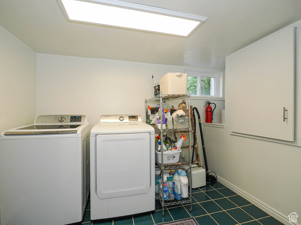 Laundry room with washing machine and clothes dryer and dark tile patterned flooring