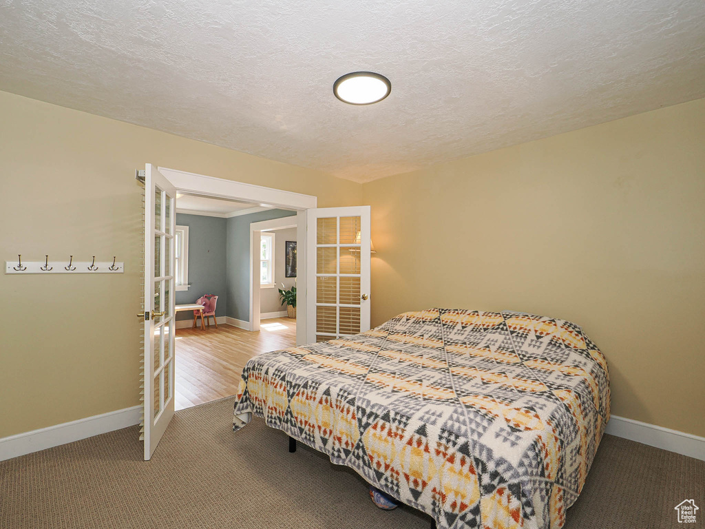 Carpeted bedroom featuring french doors and a textured ceiling