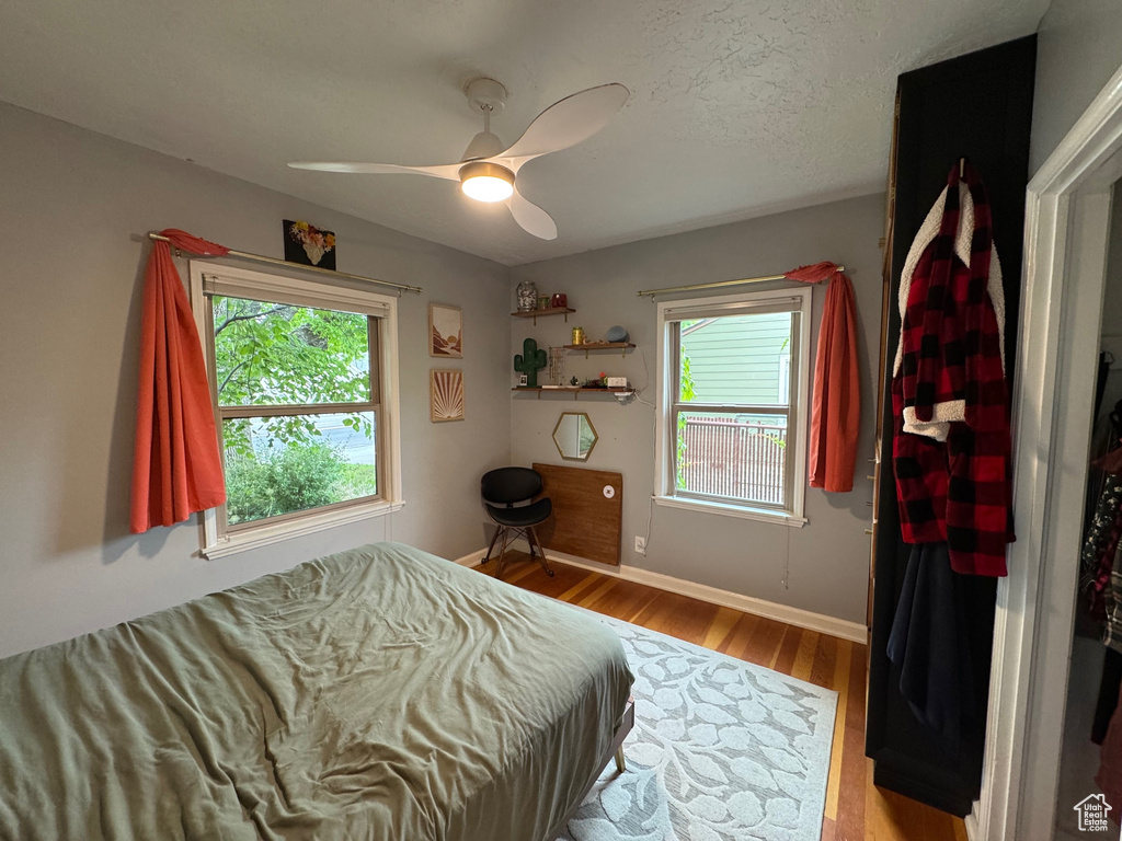 Bedroom with multiple windows, wood finished floors, and ceiling fan