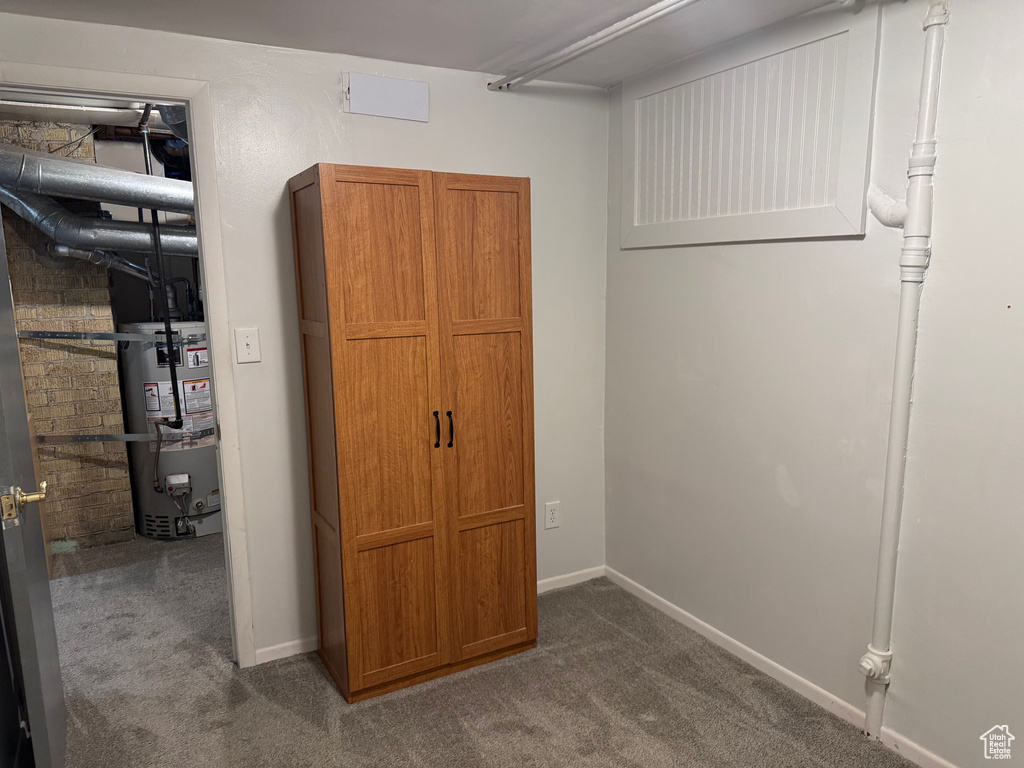 Below grade area with strapped water heater and dark colored carpet