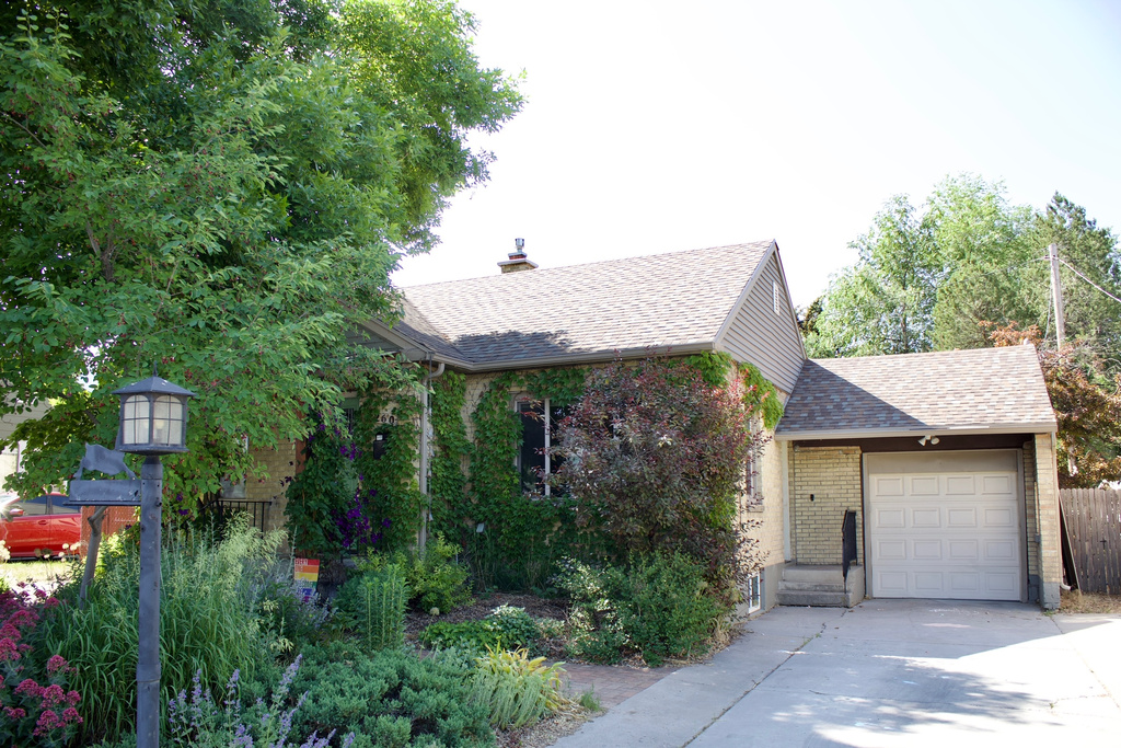 View of front of property with driveway, brick siding, roof with shingles, and an attached garage