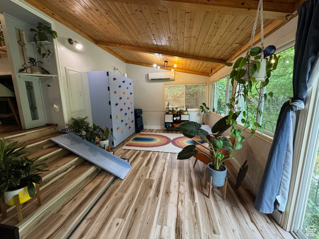 Living room with a wall mounted air conditioner, wood ceiling, healthy amount of natural light, and wood finished floors